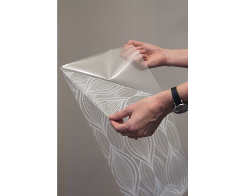 En rulle tapet med mönster hålls av två händer.