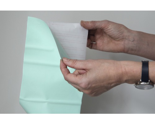 En person tar bort skyddsfilmen från en folie.