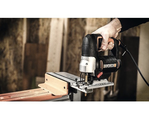 Hand håller sticksåg vid sågning av trä