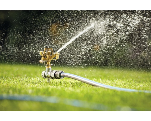 Grässpridare som vattnar en gräsmatta