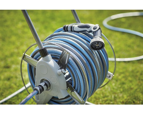 Upprullare med trädgårdsslang och sprutmunstycke i trädgården