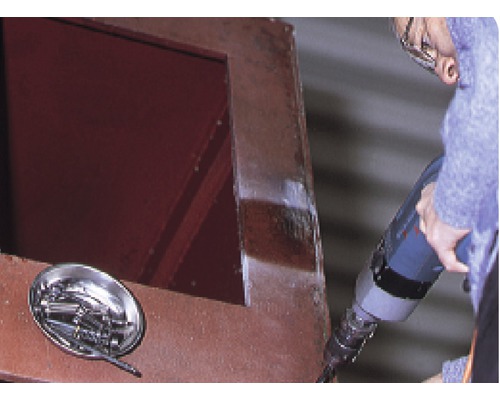 Hantverkare arbetar med borrmaskin på stålkonstruktion