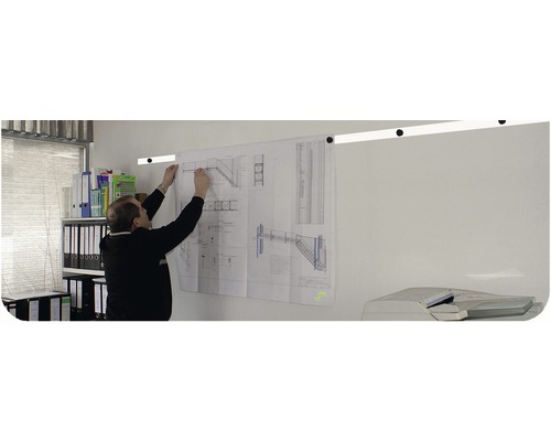 Man fäster en byggplan med trappmönster på en väggskena på ett kontor.