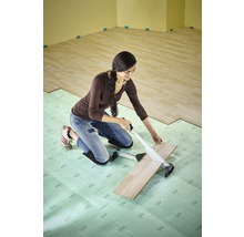 Kvinna skär laminat med en laminatskärare på ett isolerande underlag i rummet