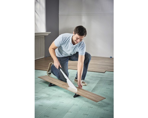 Man skär laminat med en laminatskärare på stegljudsisolering