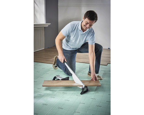 En man skär en laminatskiva med en laminatskärare.