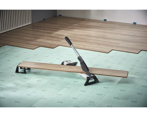 Laminatskärare i bruk på stegljudsisolering vid läggning av laminat