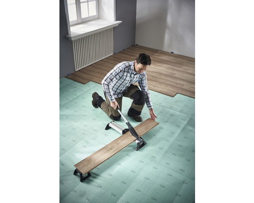 Man skär laminat med en laminatskärare på stegljudsisolering