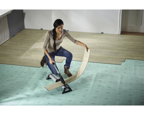 Kvinna skär laminat med en laminatskärare på ett underlagsgolv