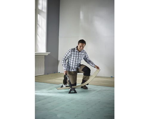 Man lägger laminat med en laminatskärare i ett rum.