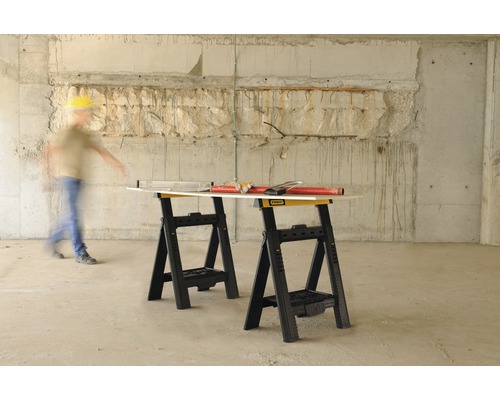 Två svarta och gula Stanley bockar med verktyg och en man i bakgrunden