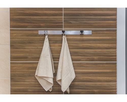 Badrumsvy med handdukar på ett handduksställ framför en vägg med träplattor