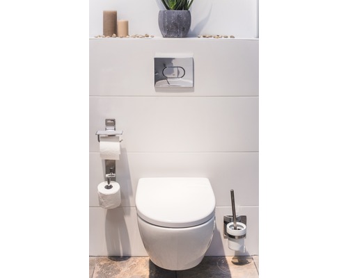 Modernt badrum med vägghängd toalett, toalettpappershållare och toalettborstset.