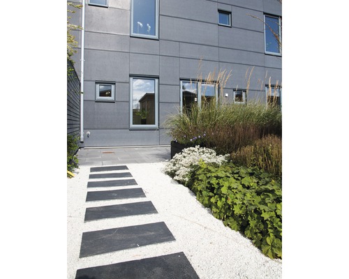 Trädgårdsdesign med trampstenar och grusgång framför ett bostadshus