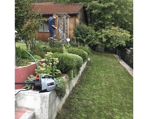 Trädgårdsbevattning med trädgårdspump framför ett hus