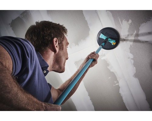 Man slipar en vägg med en gipsskivslipmaskin