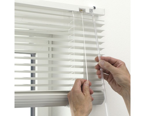 Person som använder en persienn som fönsterdekoration.