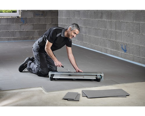 En man använder en laminatskärare för att lägga laminat.