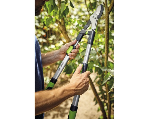 Person beskär en gren med en häcksax med utväxling