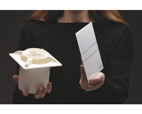 Person håller ventilationsventil och täckplatta i handen