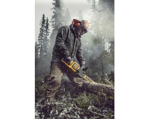 En person sågar en trädstam med en DeWalt batteridriven motorsåg. Personen bär skyddskläder och arbetar utomhus.