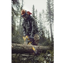 Man med skyddskläder och motorsåg som sågar ved i skogen