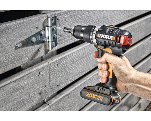 Sladdlös skruvdragare som fäster ett gångjärn på ett trästaket