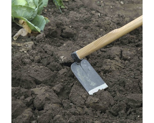 Hacka med träskaft i trädgårdsjorden