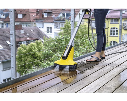Kvinna rengör träterrass med Kärcher terrasstvätt