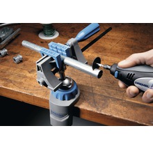 Dremel logotyp. Arbetsbänk med Dremel multiskruvstycke och Dremel multiverktyg som kapar ett rör.