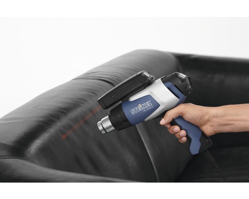 Person håller Steinel HL 2020 E varmluftspistol ovanför en skinnsoffa