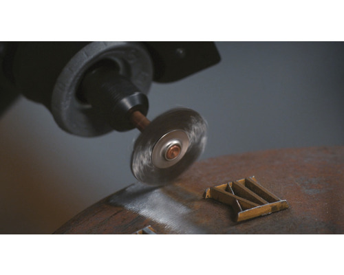 Stålborste på en borrmaskin som tar bort rost från en metallbit