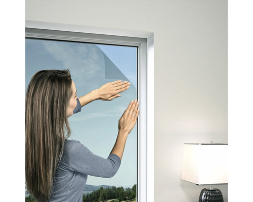 Kvinna applicerar solskyddsfilm på ett fönster
