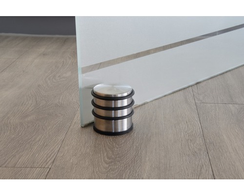 Dörrstopp i rostfritt stål framför en glasdörr