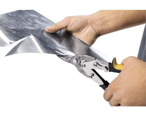 En person klipper en metallplåt med en plåtsax.