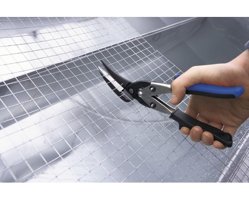 En person klipper metallnät med en plåtsax.