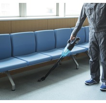 En person använder en sladdlös dammsugare i ett väntrum.