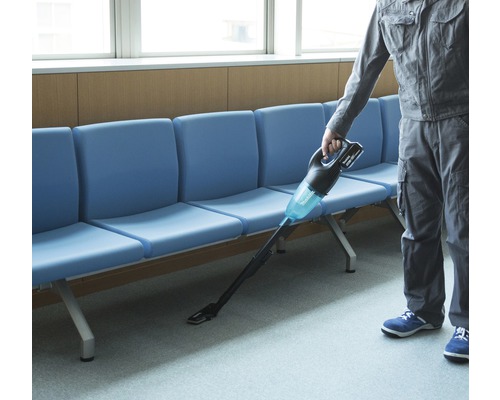 En person använder en sladdlös dammsugare i ett väntrum.