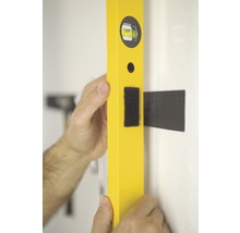 Ett gult vattenpass riktas in mot en vägg.