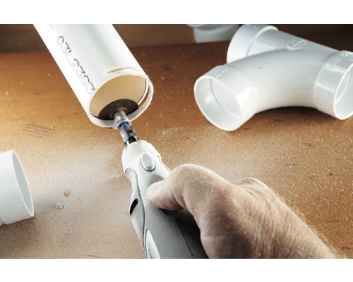 En person skär ett plaströr med ett multifunktionsverktyg.