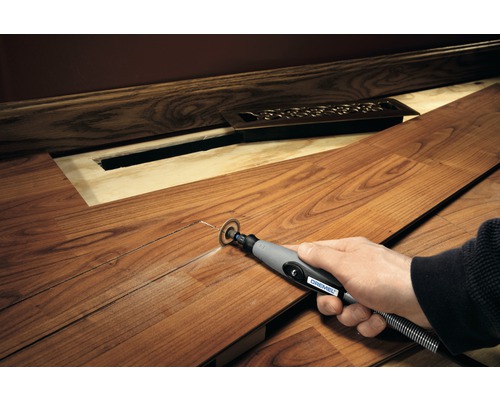 En person använder ett Dremel multiverktyg för att skära en laminatskiva för att göra plats för ett element.