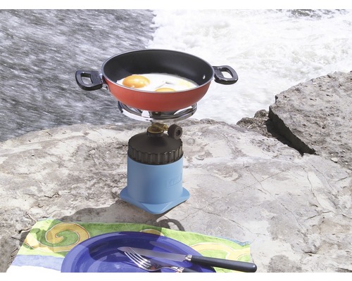 Campingkök med stekt ägg och porslin på en sten