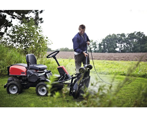 Man rengör åkgräsklippare på en åker