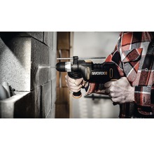 En person borrar i en tegelvägg med en Worx slagborrmaskin.