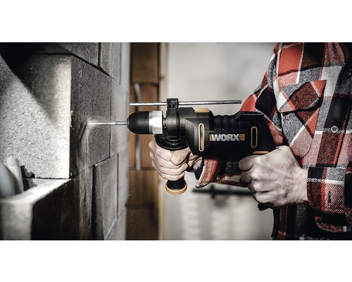 En person borrar i en tegelvägg med en Worx slagborrmaskin.