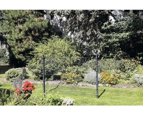 Trädgårdsscen med stängselelement av metall framför blommande buskar