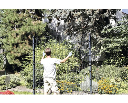 Man monterar ett dubbeltrådsstängsel i trädgården