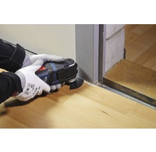 En person använder ett multifunktionellt verktyg för att skära trägolv.