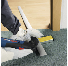 Hantverkare skär sockel med multiverktyg. Vattenpass ligger redo.