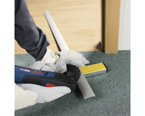 Hantverkare skär sockel med multiverktyg. Vattenpass ligger redo.